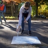 Macalester student volunteers stencil signs near storm drains in Saint Paul, Minn. to raise awareness about runoff pollution in the Mississippi River.